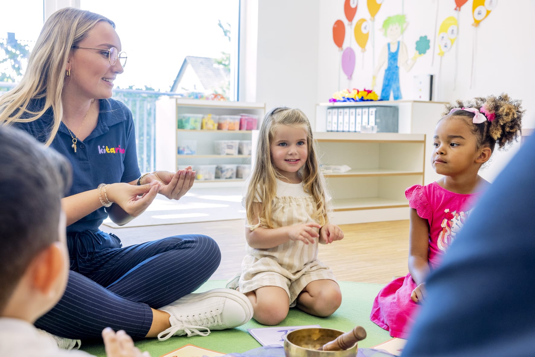 Kitarino Erzieherin sitzt mit den Kindern im Kreis