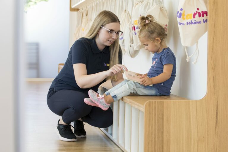 Kind sitzt mit Buch auf der Garderobe Kitarino