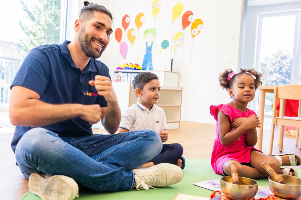 Kinder sitzen mit Klangschalen am Boden