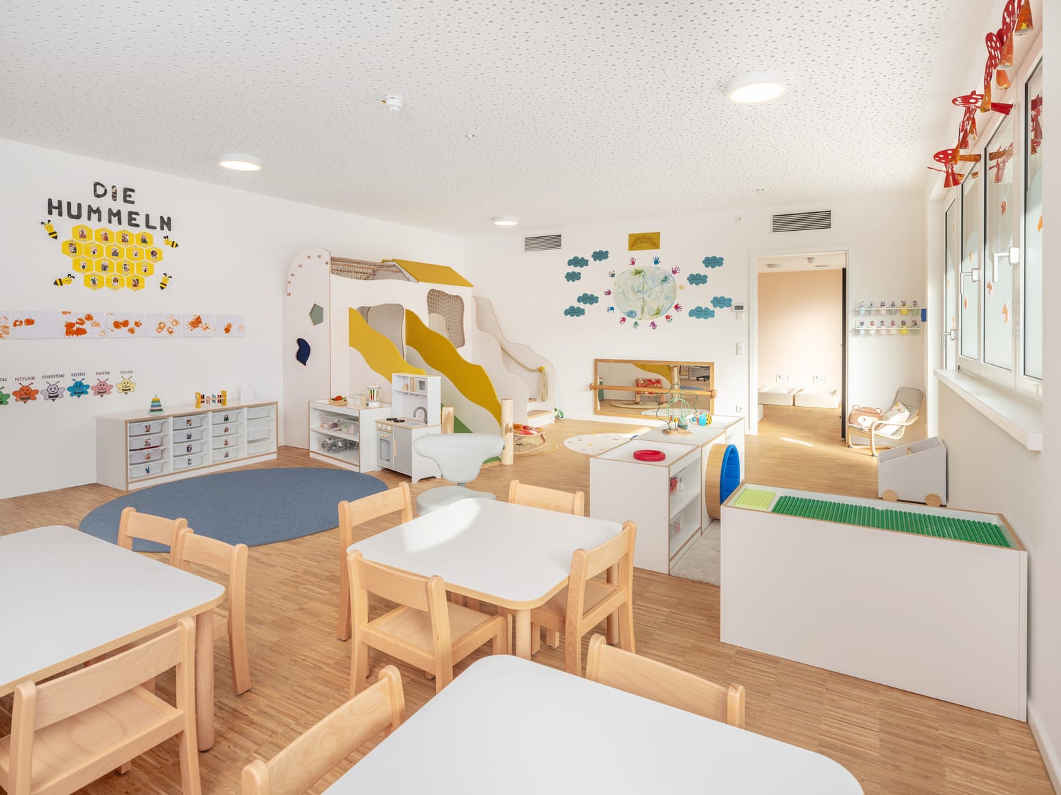 Gruppenraum mit Spielebene und Regalen auf Kinderhöhe